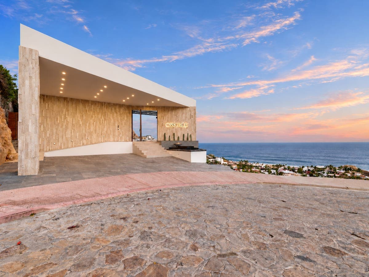 Casa True sunset exterior — gold lettering on stone, ocean beyond
